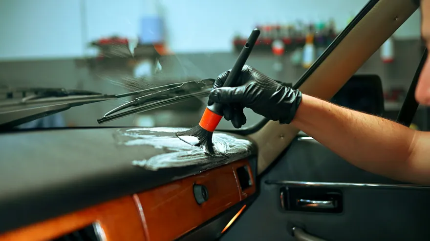 A detailing brush cleaning the dashboard of a classic car