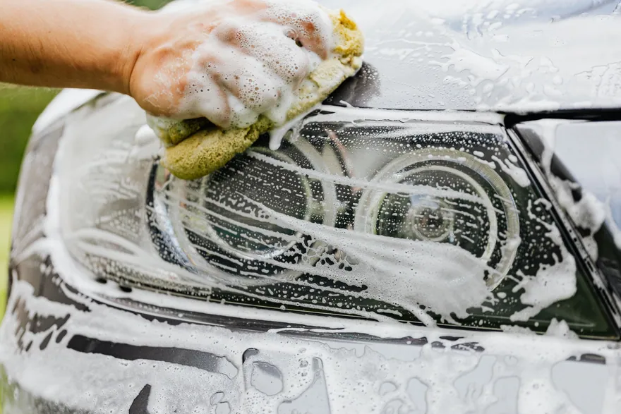 A soapy sponge working over a car headlight
