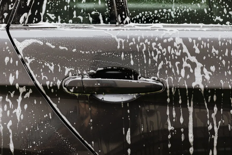 Soap suds running down the door of a freshly washed car