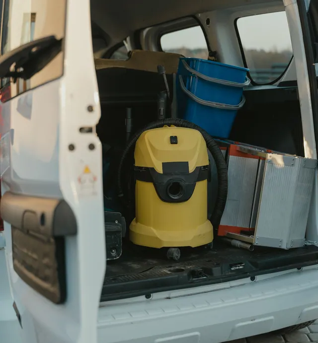 The open back of a detailer’s van with a yellow vacuum, buckets and cleaning gear, ready to drive to the customer