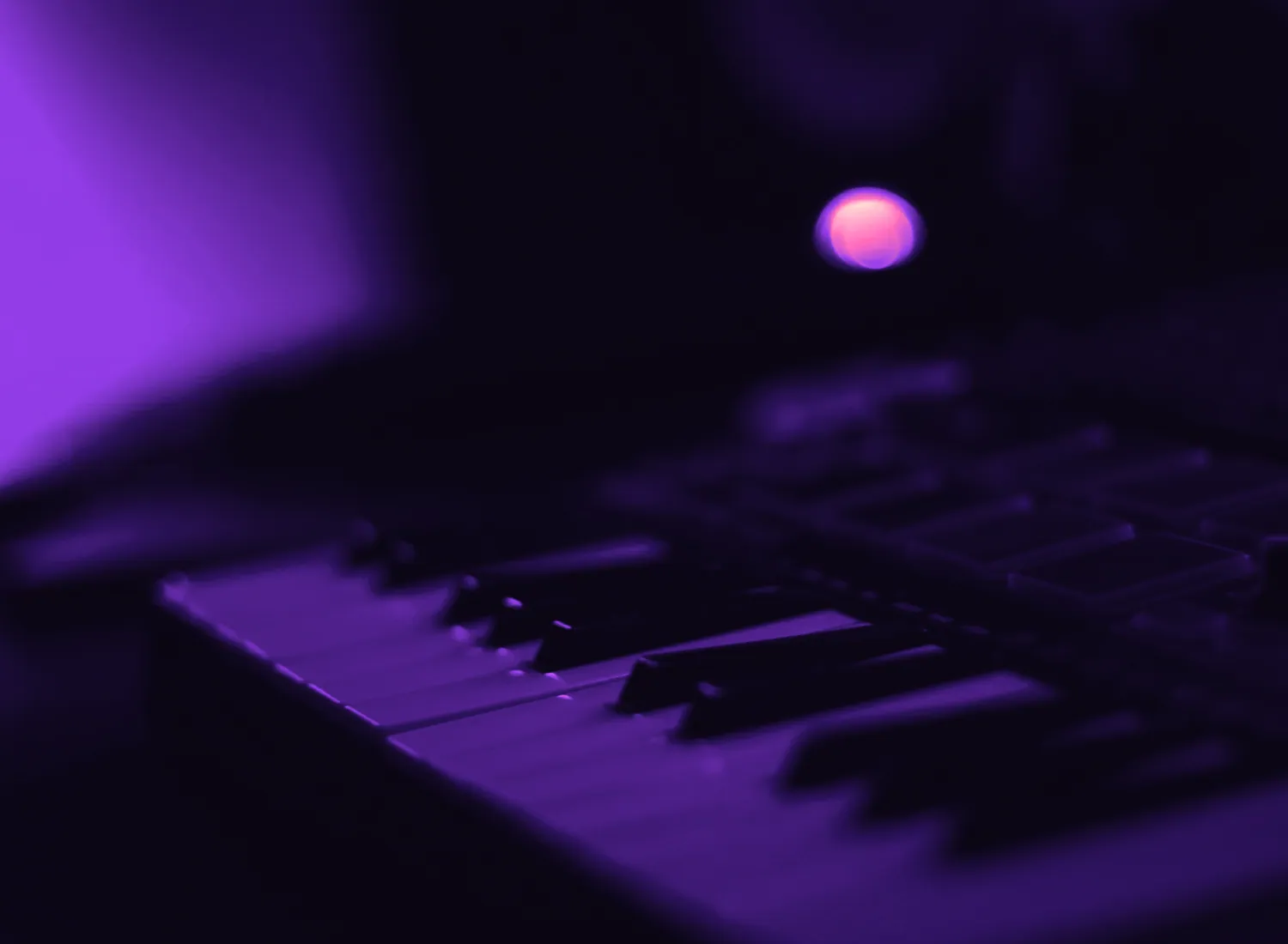 Close-up of a keyboard and drum pads in violet light
