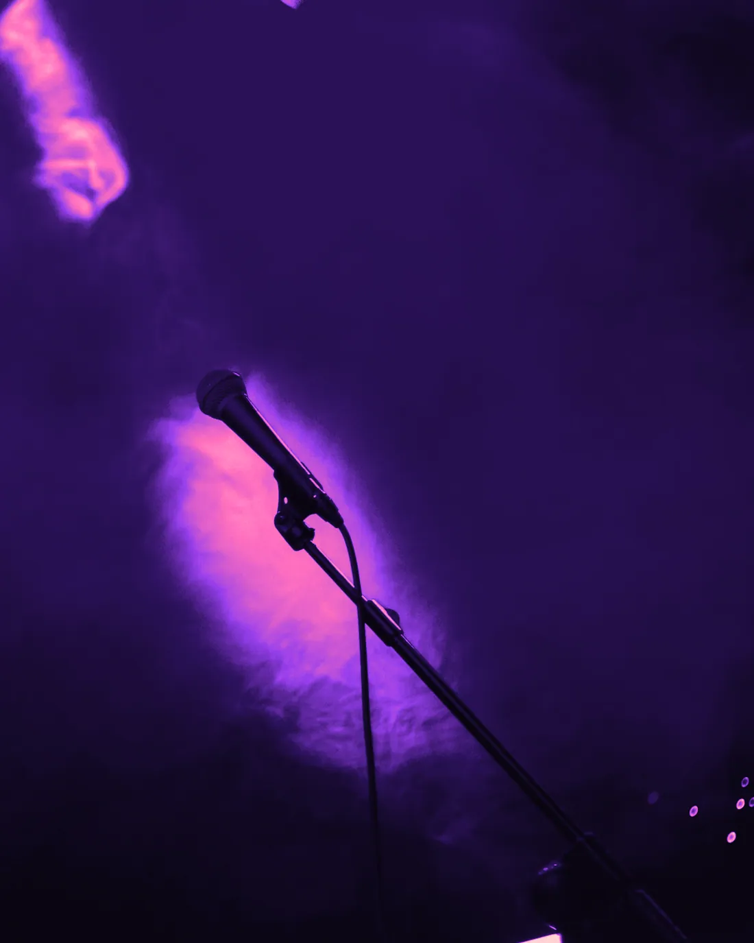 A microphone on a stand in front of hazy stage light