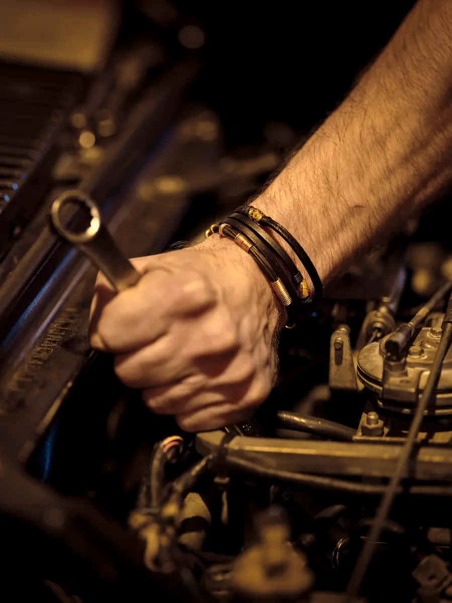 A mechanic’s hands tightening a bolt in an engine bay with a wrench
